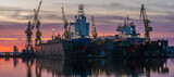 Fototapeta Maki - Ship repair at the ship repair yard during a spectacular sunrise-panorama