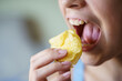 Crop young girl with mouth wide open about to eat potato chips