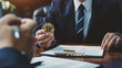 Businessman hand holding gold bitcoin coin with document on desk in office