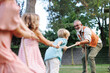 © Halfpoint - Grandfather has a tug of war with their grandkids. Fun games at family garden party.