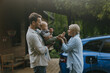 © Halfpoint - Young family with baby standing by their electric car. Electric vehicle with charger in charging port.