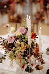 Wall Mural - Red flower arrangements in vases, colorful decor, autumn flowers. On the festive table in the wedding banquet area, compositions of flowers and greenery, candles are placed.