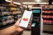 © Татьяна Евдокимова - Person using smartphone to pay at a modern self-service checkout in a store