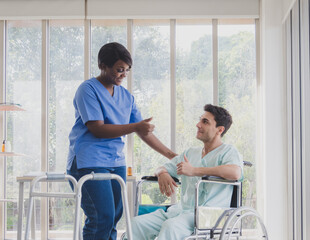 Portrait patient caucasian man sit wheelchair with woman nurse carer physical therapist African-American two people talk helping support give advice feel relax smile happy in hospital room service.