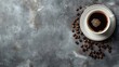 Top view of a freshly brewed espresso in a white cup with scattered coffee beans on a gray surface.