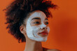 Woman facial clay mask. Beautiful black girl with cosmetic peel off mask on her face. Natural skin care and cleansing concept. Beauty and spa treatment