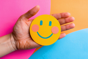 Hand holding happy smile face and sad paper cut, Positive thinking, Mental health assessment , World mental health day concept. A person is holding two smiley faces in their hands. faces are smiling