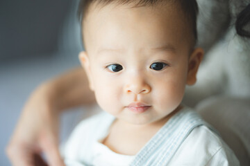 Portrait of enjoy happy love family asian mother playing with adorable little asian baby newborn infant, Mom touching care with cute son in a white bedroom.Love of family concept