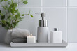 Toiletries - towels, soap dispenser in grey color, flowers in a vase