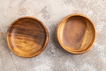 Two empty brown wooden bowl on brown concrete. Top view, copy space