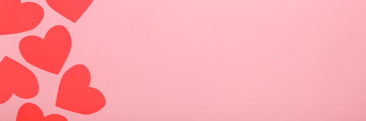 Wall Mural - Red heart shapes from application paper on light pink table background. Pastel color. Love concept. Wide banner. Closeup. Empty place for text. Top down view.