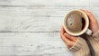© Roza - Hand of a girl holding a coffee cup, on a light wooden background, top view, free space