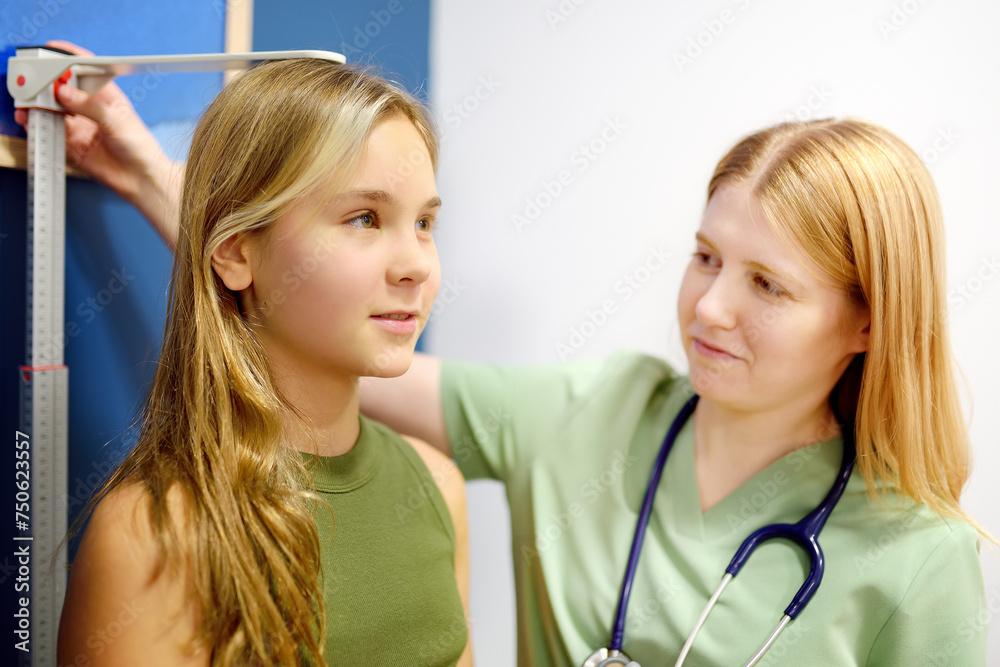 Female doctor measuring of teenage girl height. Schoolgirl patient is at pediatrician appointment. Healthcare for kids.