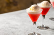cold cocktail. on a white kitchen table there are triangular glasses on a long stem, with a pink drink and scoops of vanilla ice cream, close-up, drink concept