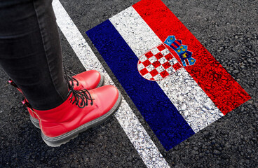 Wall Mural - a woman with a boots standing on asphalt next to flag of Croatia and border
