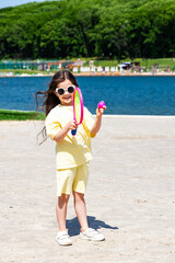 Wall Mural - Little girl playing tennis on the city beach. The concept of sports and active games in summer, recreation, lifestyle.