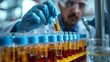 © Old Man Stocker - Focused lab technician examines a test tube with a yellow liquid against the light in a scientific research laboratory.