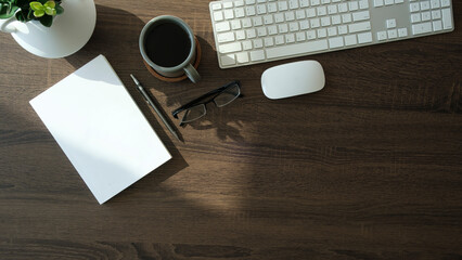 Wall Mural - Simple workplace notebook, coffee cup and wireless keyboard on wooden table. Top view..