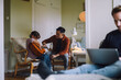 © Maskot - Father teaching daughter to play guitar while sitting on chair at home