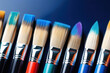 Artists paintbrushes in a row on black paper background. Bright colorful art tools for drawing, brush with synthetic bristle for paint closeup.