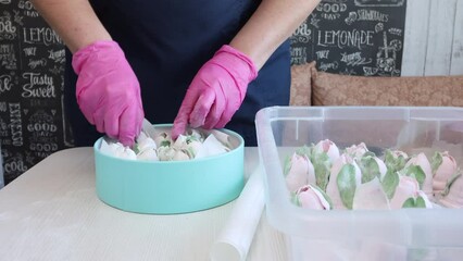 Wall Mural - A woman puts a homemade marshmallow in a box.  The box is turquoise in color. There are zephyr tulips on the table next to it