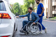 © zinkevych - Man in a wheelchair opening a car door