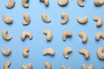 Wall Mural - Many tasty cashew nuts on light blue background, top view