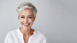 Elderly woman with smooth healthy facial skin on gray background. Aging mature woman with short gray hair, happy face. Concept of advertising beauty and cosmetics for women's skin care. Copy space.
