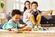 © LIGHTFIELD STUDIOS - focus on jolly african american boy playing with his cheerful blurred mother and brother on backdrop