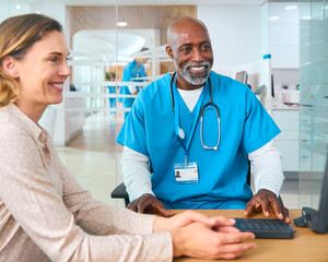 Sticker - Mature Male Doctor Wearing Scrubs At Hospital Appointment With Female Patient Looking At Computer