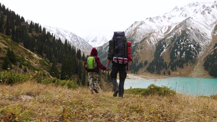 a father and son are hiking in a mountainous area. view from the back. active time spent in outdoors