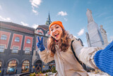 Fototapeta Paryż - A cheerful young woman explores the charming city of Subotica, Serbia, her vibrant energy adding to the lively ambiance of the historic town hall square.