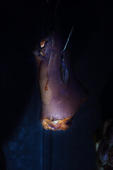 Smoked pork meat in smokehouse on dark background. Close-up of well smoked meat in a net hanging in a home smokehouse .
