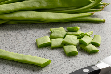 Sticker - Fresh raw green flat beans and slices on a cutting board close up for cooking 