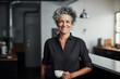 © okrasiuk - Laughing middle aged 50's stylish, confident mature woman with gray hair and tattoos in casual business outfit standing on office kitchen. Stylish senior hipster woman at work. Authentic lifestyle.