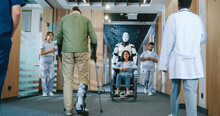 Helpful Automated Futuristic Robot Pushing Wheelchair With Young Female Patient In Digitalized Hospital. Useful Digital Bot Serving In Modern Clinic Helping People. Technological Development.