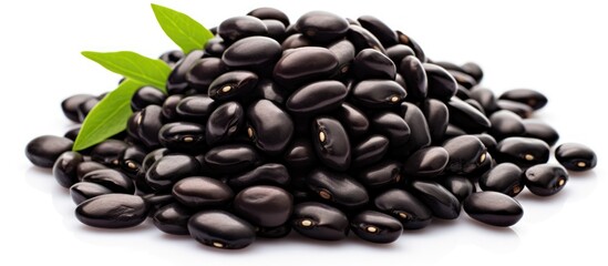 Wall Mural - A large pile of black beans is heaped together, with a vibrant green leaf placed on top. The contrast of the black beans against the isolated white background enhances the visual impact.