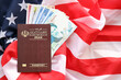Red Islamic Republic of Iran passport and money on United States national flag background close up. Tourism and diplomacy concept