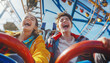 Portraits of two teenagers couple in love or brother and sister emotional screaming and laughing moment while they enjoying Roller coaster Funny time attraction ride on city carnival entertainment.