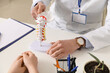 © Pixel-Shot - Male doctor explaining spinal anatomy with vertebral column model to patient in clinic, closeup