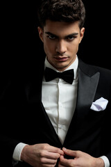 Wall Mural - handsome guy model in black tuxedo arranging his suit