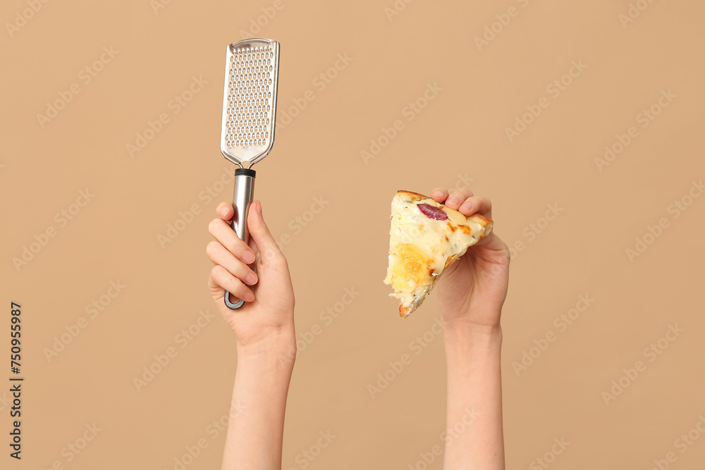 Female hands holding pizza slice and grater on beige background