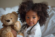 Cute curly haired black African-American girl with stethoscope and toy bear playing at home