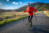 Fototapeta Góry - un homme âgé sur des ski-roues en plaine campagne  sur une route goudronnée