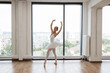 © sofiko14 - Young ballet dancer - Harmonious pretty woman with tutu posing in studio - Contemporary dance performer. Beautiful ballerina practice ballet positions in white skirt near large window in white hall.