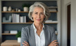 © Islam - Smiling confident stylish mature middle aged woman standing at home office. Mature businesswoman, gray-haired lady executive business leader manager looking at camera arms crossed
