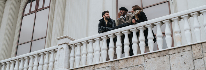 Sticker - A multicultural group of friends share a moment of joy and connection while standing on a historic balcony with elegant architecture.