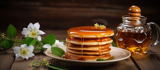 Wall Mural - A stack of freshly made pancakes is seen resting on top of a plain white plate set against a wooden background. The pancakes appear fluffy and golden brown, possibly drizzled with honey.