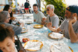 © Jimena Roquero/Stocksy - Multigenerational group of people sitting by restaurant terrace table