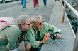© Jimena Roquero/Stocksy - Senior tourist couple filming on videocamera in the street